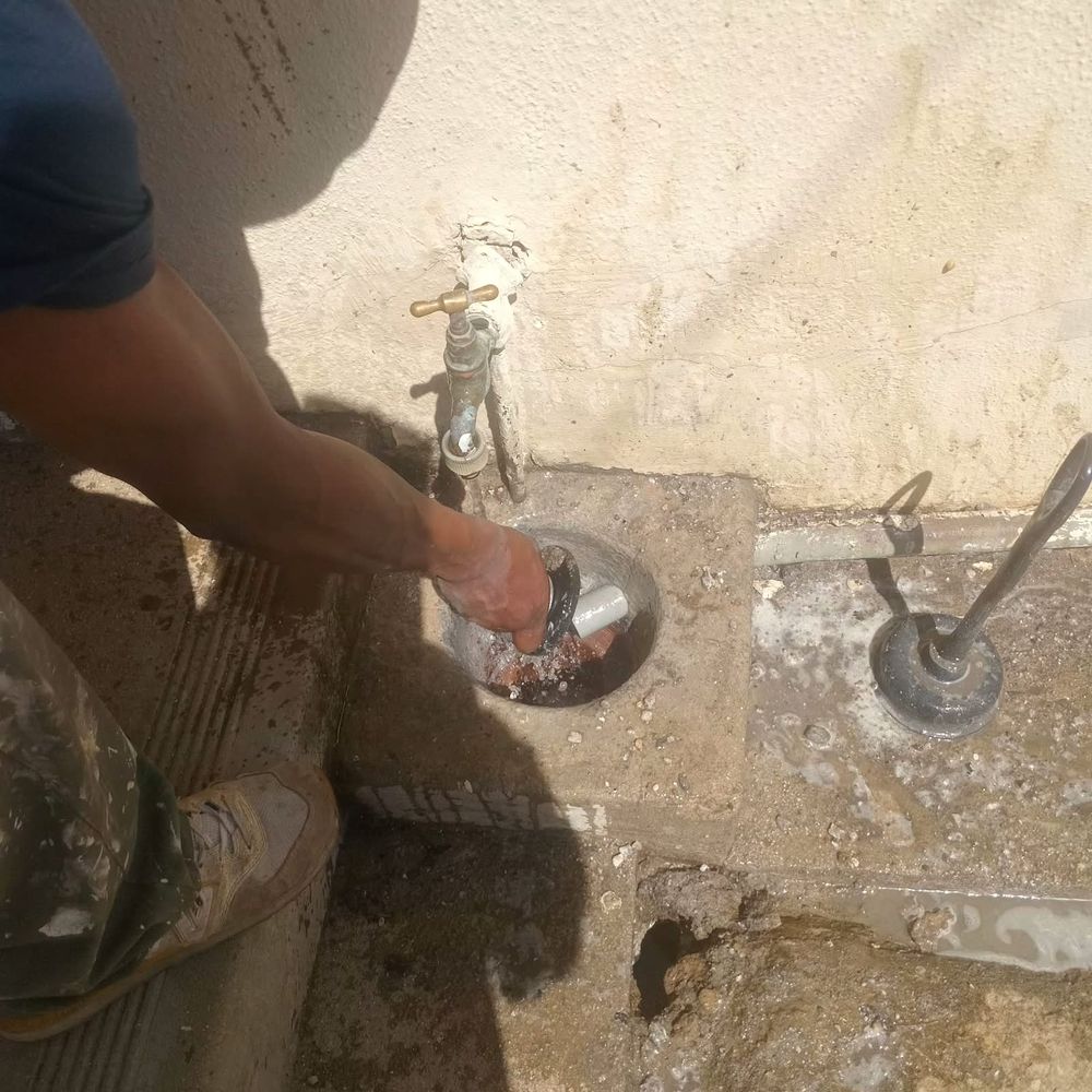 A plumber clearing a blocked outside gully beside a garden tap