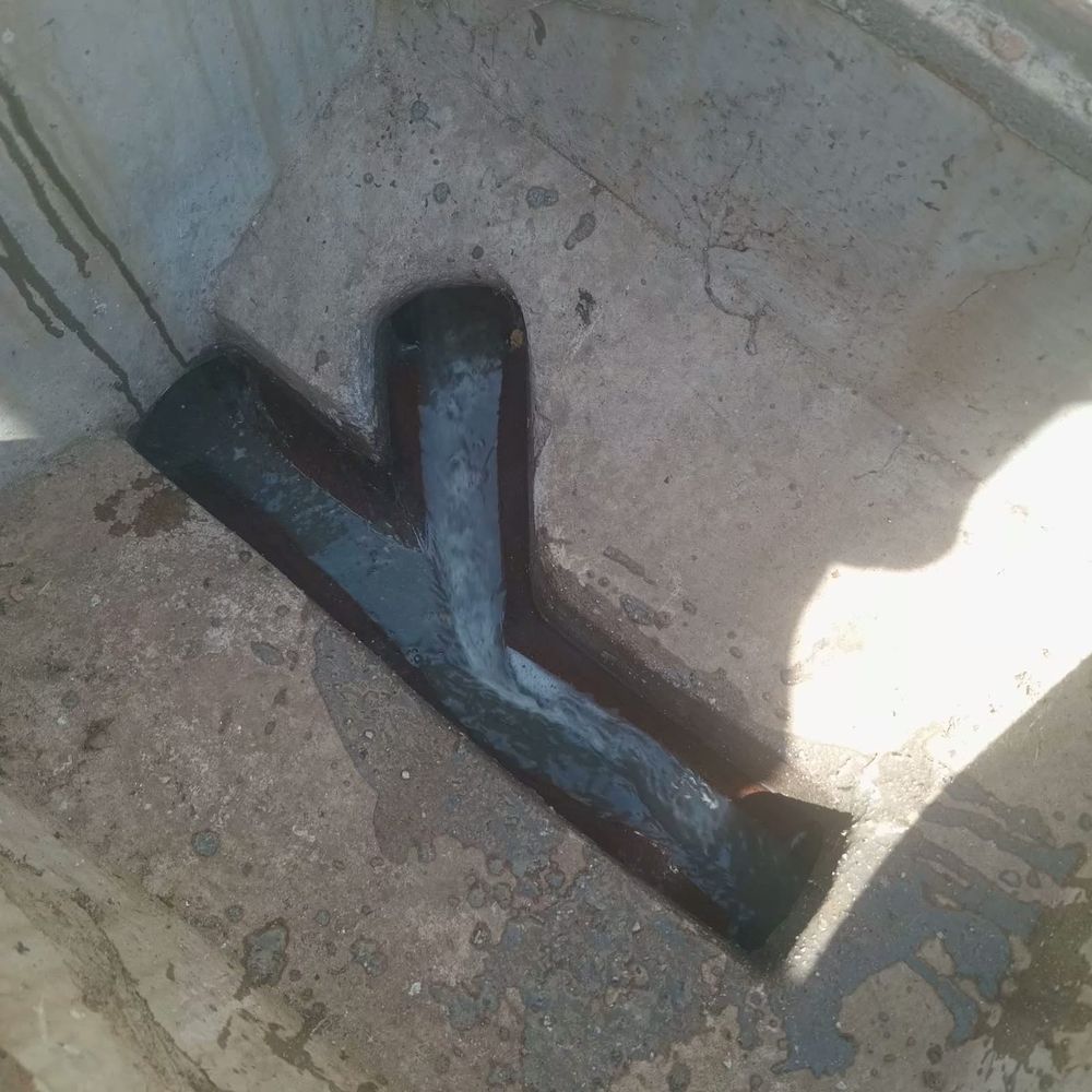 Water running freely through the Y-junction channel of a sewer inspection chamber